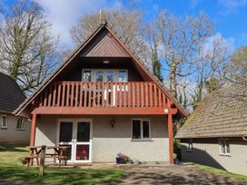 A house with a balcony and patio furniture at Mayfly Lodge St Tudy