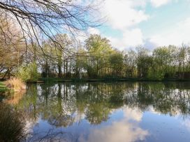 A pond surrounded by trees and grass at Mayfly Lodge St Tudy