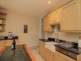 A kitchen with a sink, dishwasher, and wine bottle at Shipwrights, Salcombe