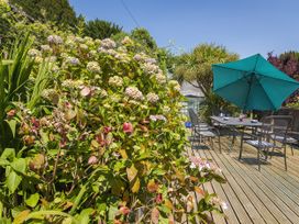 A garden with flowers and a table set with chairs at Shipwrights in Salcombe