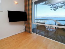 A living room with a television and a view of the water at 20 Heath Court in Brixham