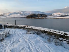 A snowy landscape with water and hills at The Cabin in Crawshawbooth