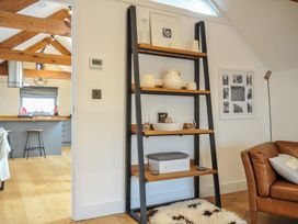 A living room with a shelf displaying decor and a kitchen in the background at The Dairy