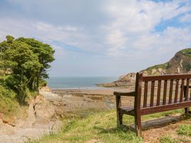 A view of the sea and beach with a bench at The Dairy in Bridgerule