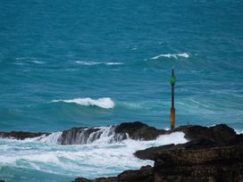 An ocean view with waves and a buoy on a rocky shore at The Dairy in Bridgerule
