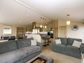 A living room with a kitchen area and seating at The Hideaway in Pwllheli