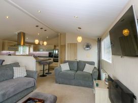 A living room with a sofa, coffee table, and kitchen area at The Hideaway in Pwllheli