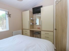 A bedroom with a bed, desk with a mirror, and television at The Hideaway in Pwllheli