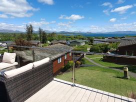 A balcony with a sofa overlooking houses and landscape at The Hideaway in Pwllheli