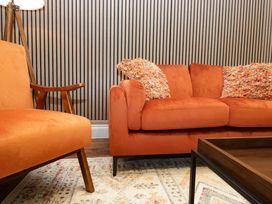A living room with orange sofa and armchair at The Studio in Windermere