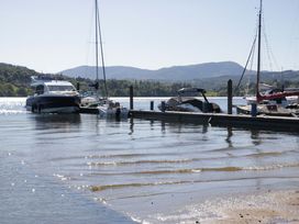 A dock with boats on water and mountains in the background at The Studio Windermere