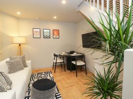 A living room with a sofa, dining area and television at The Coach House in Windermere
