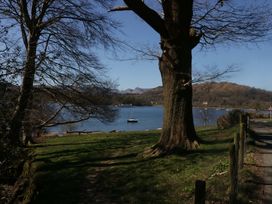 A view of a lake with a boat near a tree at The Coach House in Windermere