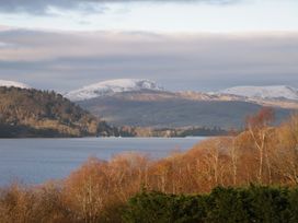 A lake with mountains and trees at The Coach House in Windermere