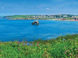 A view of a rock formation in the ocean with flowers and grass at 8 Thurlestone Rock in Kingsbridge