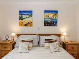 A bedroom with a bed and paintings at 8 Thurlestone Rock in Kingsbridge