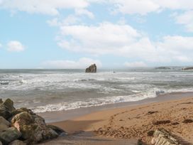 A beach scene with waves and a prominent rock formation at 8 Thurlestone Rock in Kingsbridge