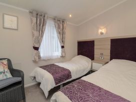A bedroom with two beds and a chair at Whistler in Wimborne