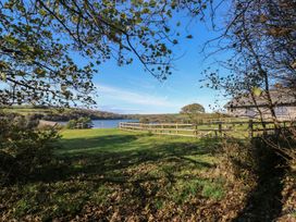 A view of a body of water with a fence and trees at Carthouse Cottage in Clarbeston Road