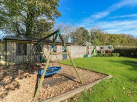 A garden with a swing set, playhouse, and slide at Carthouse Cottage, Clarbeston Road