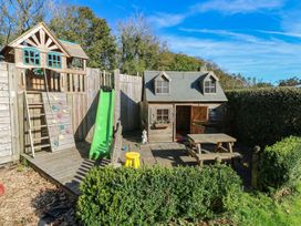 A play area with a wooden playhouse and slide at Carthouse Cottage in Clarbeston Road
