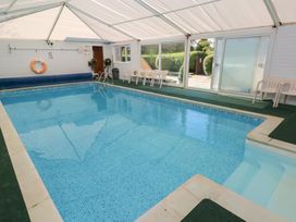 An indoor swimming pool with deck chairs at Carthouse Cottage in Clarbeston Road