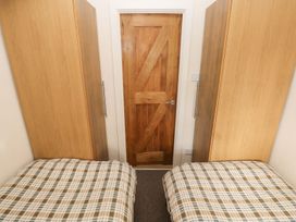 A bedroom with two beds and wooden wardrobes at Knap Cottage Clarbeston Road
