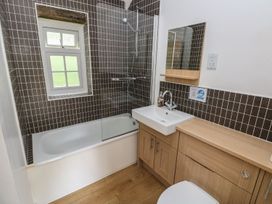 A bathroom with a bathtub, shower, sink, and mirror at Corner Cottage in Clarbeston Road