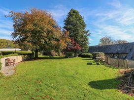 A garden with trees and benches at Corner Cottage Clarbeston Road