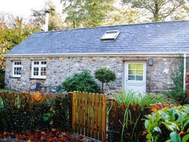 A stone cottage with a fenced yard and chairs at Corner Cottage in Maenclochog