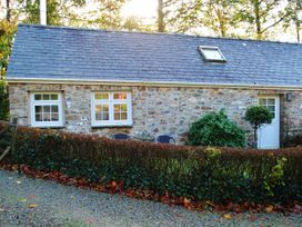 A stone cottage with windows and a door surrounded by a hedge at Corner Cottage in Maenclochog