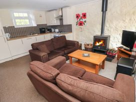 A living room with a wood stove and kitchenette at Stable Cottage in Clarbeston Road