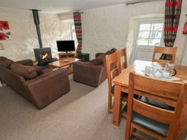 A living room with a sofa, dining table and wood stove at Stable Cottage in Clarbeston Road