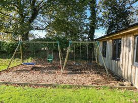 A garden with swings and a wooden building at Swallows Cottage in Clarbeston Road