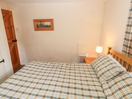 A bedroom with a bed and a lamp at Granary Cottage in Clarbeston Road