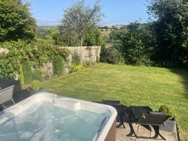 A garden with a hot tub and deck chairs at Newlands in Yelverton