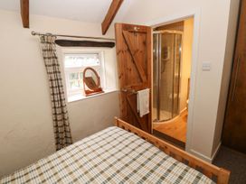 A bedroom with a bed and a bathroom door at Rafters Cottage in Clarbeston Road