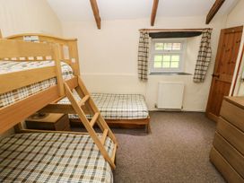 A bedroom with a bunk bed and a single bed at Rafters Cottage, Clarbeston Road
