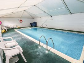 An indoor pool area with a pool ladder and plastic chairs at Rafters Cottage in Clarbeston Road
