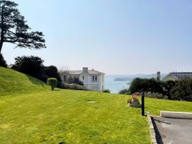 A lawn with a house and water view at Number 2 Ellington Court Apartment Torquay