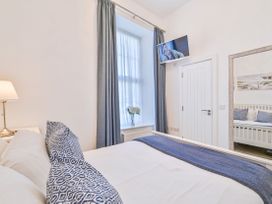 A bedroom with a bed, television, and a door at Number 2 Ellington Court Apartment in Torquay