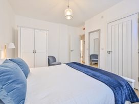 A bedroom with a bed, lamp, wardrobe, and chair at Number 2 Ellington Court Apartment in Torquay