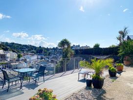 A garden with a table and chairs overlooking a view at Ockendon House Apartment B in Torquay