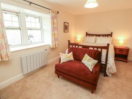 A bedroom with a bed and armchair at East View in Ravenstonedale near Kirkby Stephen