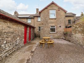 An outdoor area with a wooden table and stone walls at East View Ravenstonedale near Kirkby Stephen