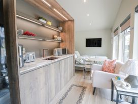 A kitchenette with appliances and a bed in a studio at Cabin At The Brig Annan