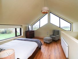 A bedroom with a bed and armchair at The Rookery in Rosslare Harbour, County Wexford