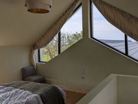 A bedroom with a bed and windows at The Rookery in Rosslare Harbour, County Wexford
