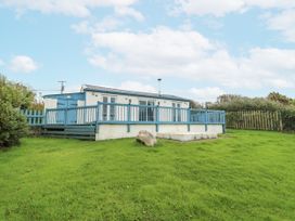 A house with a deck and green grass at Harbour Lights in Holyhead
