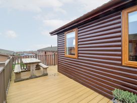 An outdoor deck with a wooden table and chairs at Ocean Terrace 28 in Ilfracombe